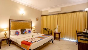 A hotel room with a bed, bedside tables, a chair, a desk, and curtains. - King’s Abode - Luxuria Ranakpur by Moustache (Desuri)