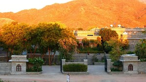A building with a stone facade, surrounded by trees and a mountainous backdrop. - King’s Abode - Luxuria Ranakpur by Moustache (Desuri)