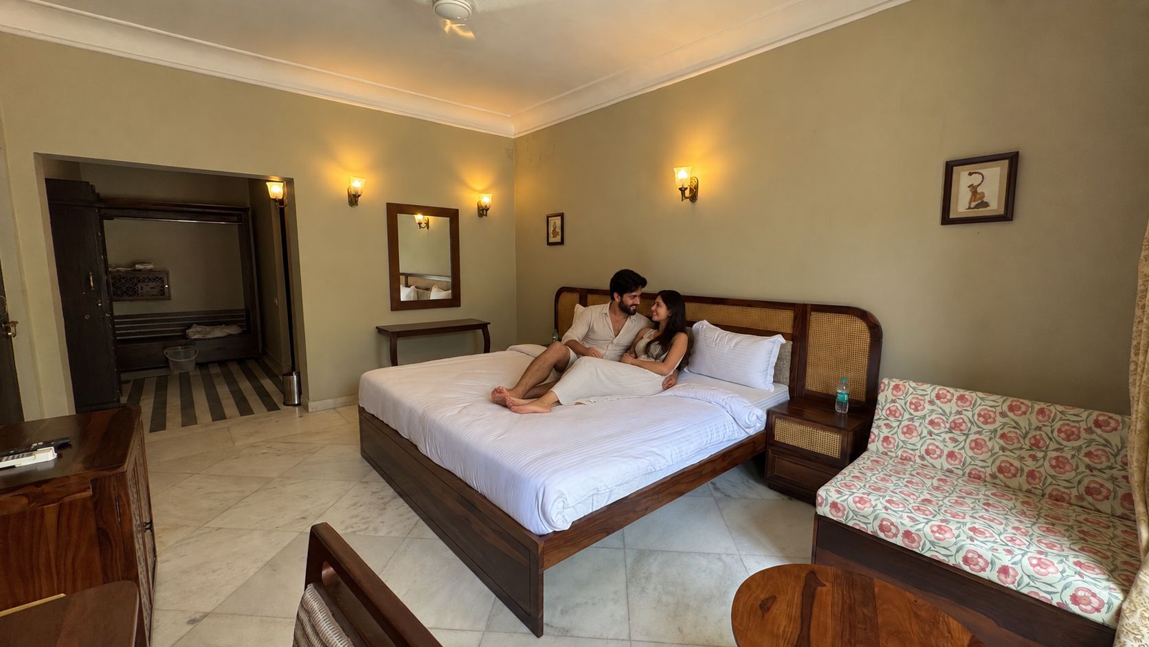A bedroom with a bed, bedside tables, a bench, and a door leading to a bathroom.