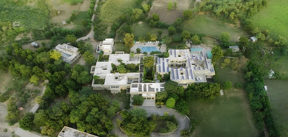 An aerial view of a residential area with multiple buildings, a swimming pool, and surrounding greenery.