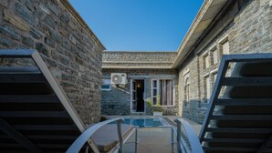 A narrow courtyard with stone walls, a staircase, and a door leading to a building. - King's Abode Ranakpur (Desuri)