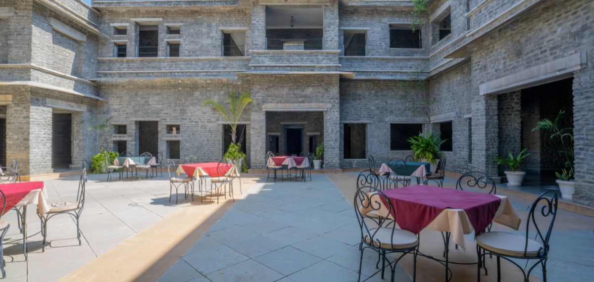 A courtyard with outdoor seating, stone walls, and potted plants.