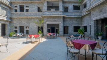 A courtyard with outdoor seating, stone walls, and potted plants.