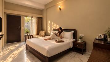 A hotel room with a large bed, a desk, a chair, a TV, and a door.