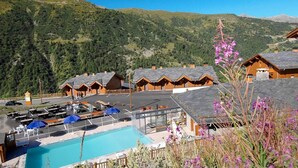 A mountain resort with wooden cabins, a swimming pool, and a view of the surrounding hills. - Chalet, wifi, swimming pool, terrace, balcony, tv, ski locker, 45m², Valmeinier (Valmeinier)