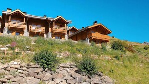 A hillside chalet with multiple wooden balconies and stone foundations. - Chalet, wifi, swimming pool, terrace, balcony, tv, ski locker, 45m², Valmeinier (Valmeinier)