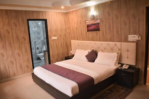 Un dormitorio con una cama grande, paredes de madera, un cuadro y un baño visible a través de una puerta de cristal.