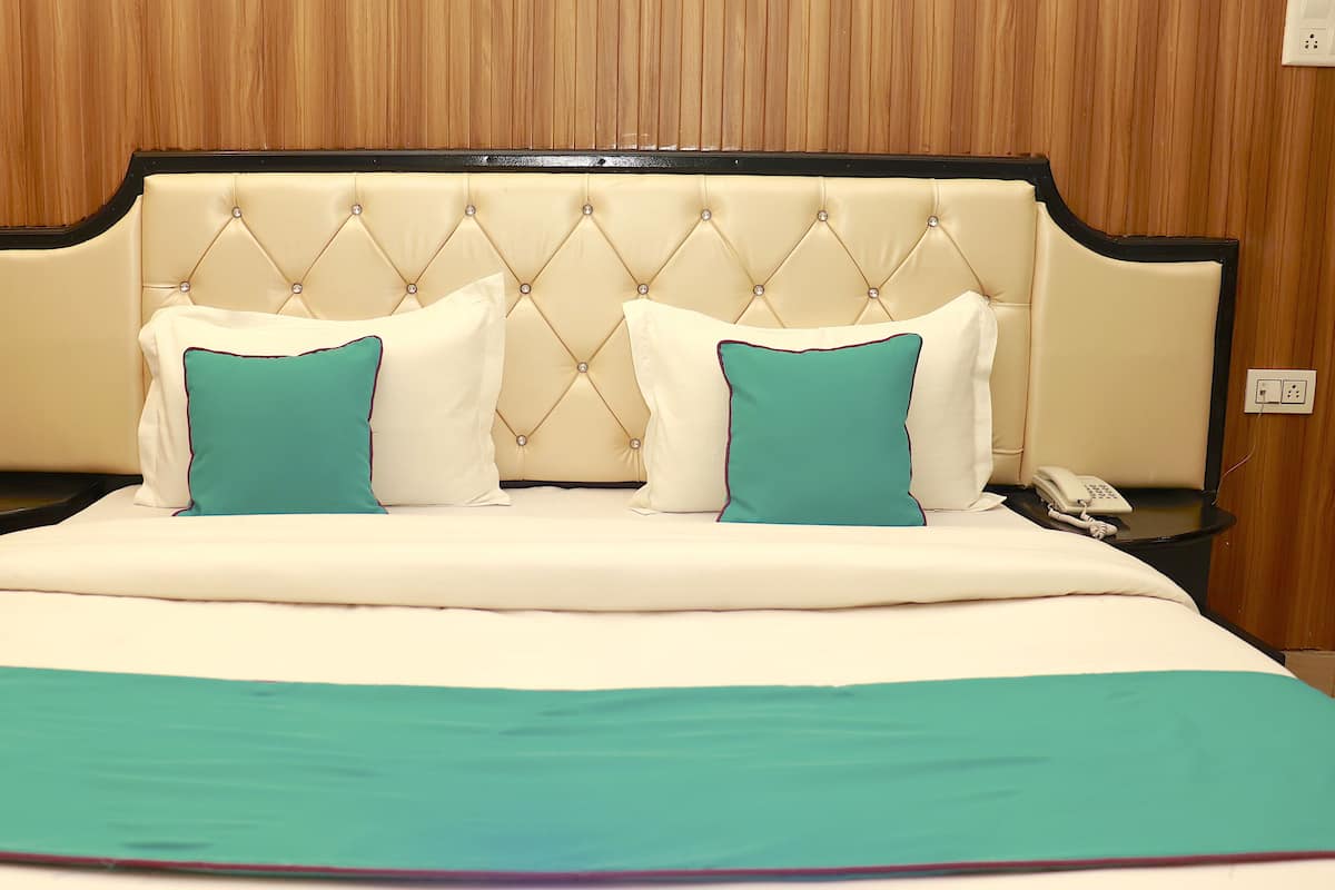 A hotel room with a large bed, two nightstands, a telephone, and a wall socket.