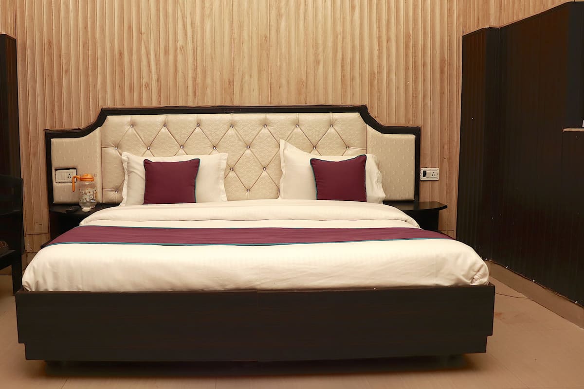 A neatly made bed with a tufted headboard, a bedside table with a lamp, and a chair.