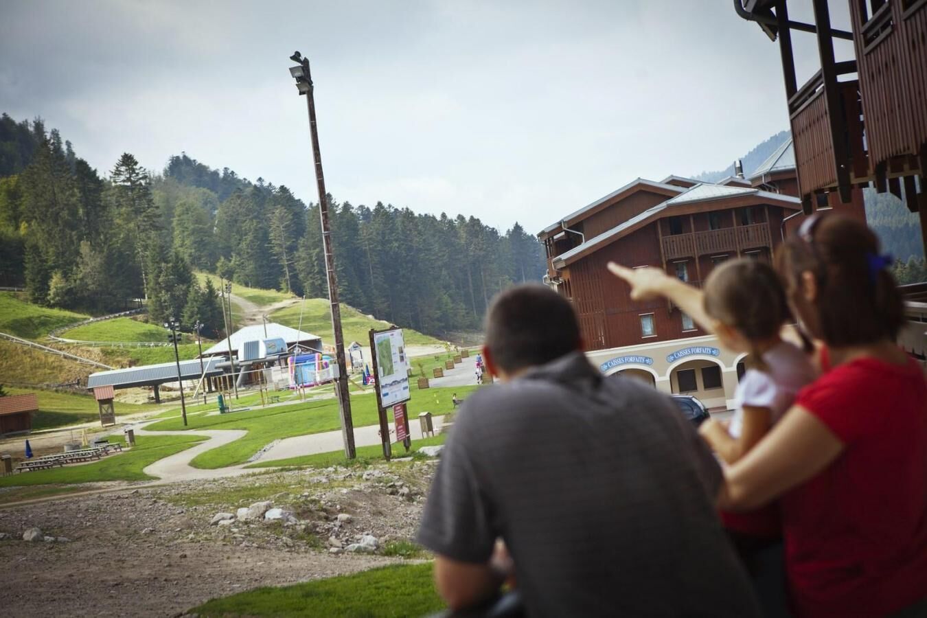 A mountain lodge with a ski lift in the background, a signboard, and a building with a sloped roof.