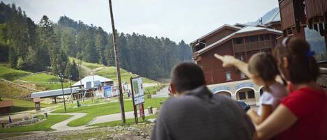 A mountain lodge with a ski lift in the background, a signboard, and a building with a sloped roof.