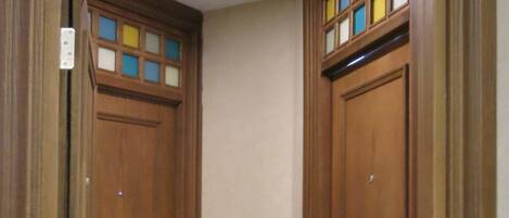 Una stanza d'angolo con due porte in legno, una piccola finestra e un interruttore a muro.
