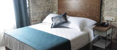 A bed with a wooden headboard, white bedding, and a blue throw blanket.