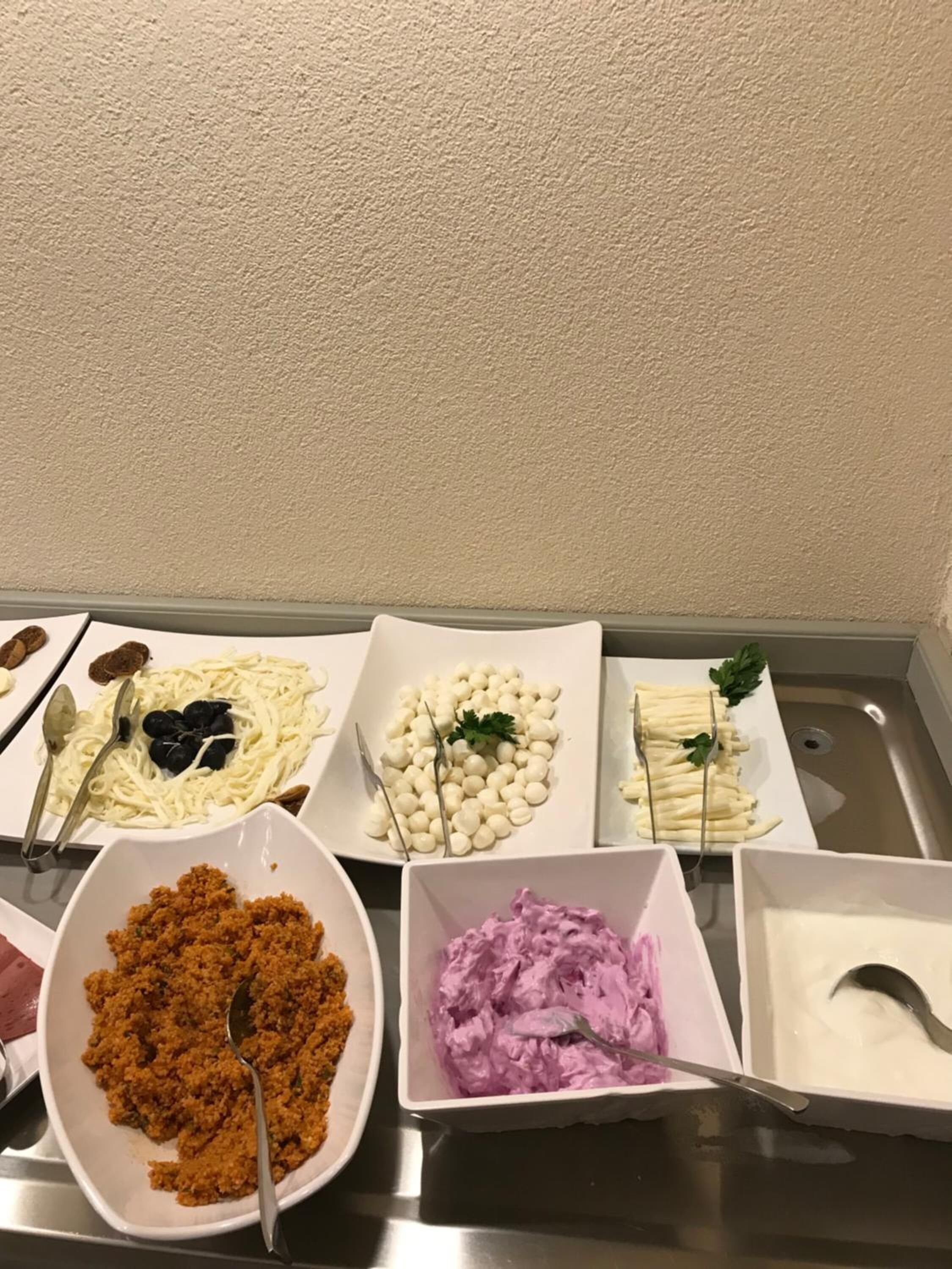 A buffet table with various dishes including pasta, cheese, and a purple dip.