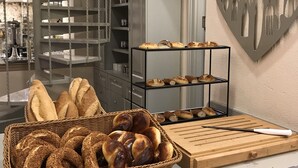 Una encimera de cocina con pan y pasteles, un cuchillo sobre una tabla de cortar y una decoración de pared con forma de corazón.