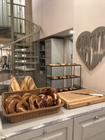 Una encimera de cocina con pan y pasteles, un cuchillo sobre una tabla de cortar y una decoración de pared con forma de corazón.