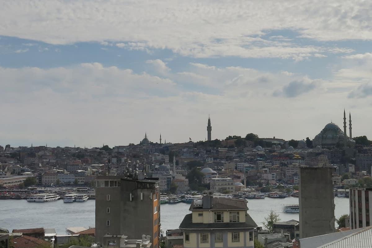 A cityscape with a river, buildings, and a mosque with a dome and minarets.