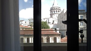 Vista a través de una ventana con balcón, mostrando un edificio histórico con una cúpula y una torre al fondo.