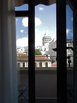 Vista a través de una ventana con balcón, mostrando un edificio histórico con una cúpula y una torre al fondo.
