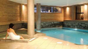 A woman sitting by a pool with stone walls and wooden paneling. - Fitness, swimming pool, sauna, hammam, terrace, balcony, tv, ski locker, 43-56m², Les Gets (Les Gets)