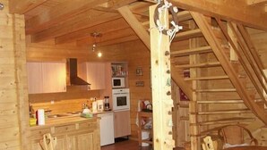 Un intérieur en bois comprenant un coin cuisine, un escalier en bois et une table à manger.
