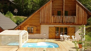 Une cabane en bois dotée d’un balcon, d’une piscine et de mobilier d’extérieur.