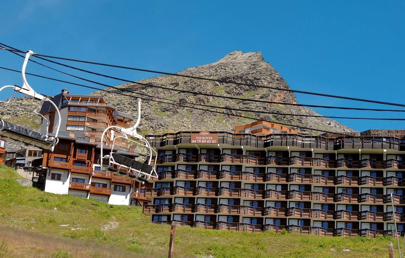 Un chalet de montagne doté de plusieurs balcons, d’un télésiège et offrant une vue sur une montagne rocheuse.