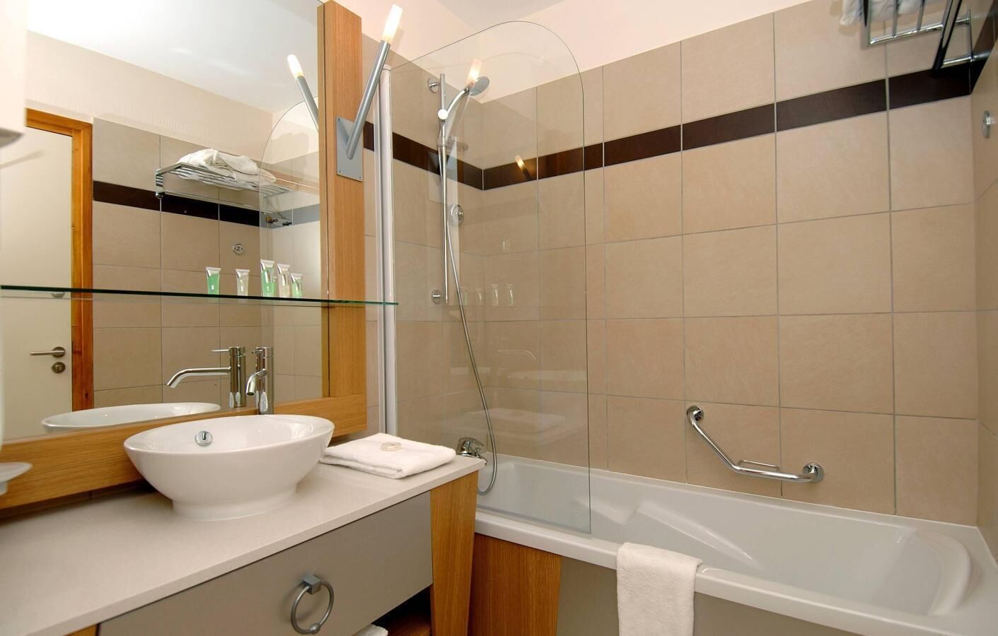 Een moderne badkamer met een douchecabine van glas, een wit wastafelmeubel en een bad.