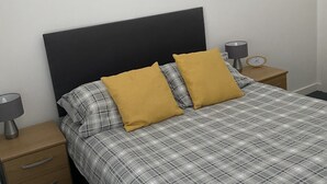A neatly made bed with a plaid bedspread and two mustard pillows, flanked by a nightstand with a lamp and a small wooden bedside table with a clock. - Pretty Properties Grange House Apartment 2 (Darlington)