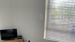 A living room with a sofa, a TV, a wooden table, and a window with blinds. - Pretty Properties Grange House Apartment 2 (Darlington)