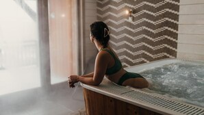 A woman in a green swimsuit sitting on a wooden edge of a hot tub. - Wifi, 100m from ski slopes, fitness, swimming pool, sauna, hammam, balcony, fireplace or stove, tv (Val Thorens)