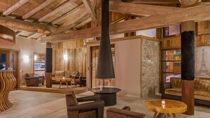 A wooden interior with a stone wall, a fireplace, and seating areas. - Wifi, 100m from ski slopes, fitness, swimming pool, sauna, hammam, balcony, fireplace or stove, tv (Val Thorens)