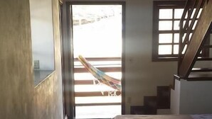 Un estrecho pasillo con una escalera que da a un balcón. Hay dos camas con ropa de cama sencilla en la habitación.