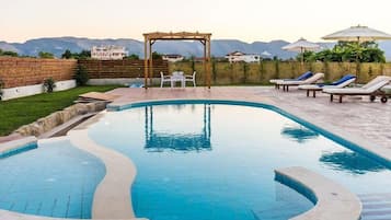 Una piscina al aire libre de temporada, sombrillas, tumbonas