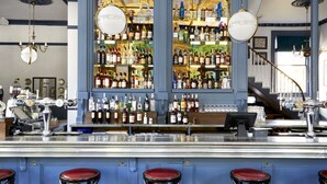 A bar area with a counter, stools, and shelves of bottles. - The Hero of Maida (London)