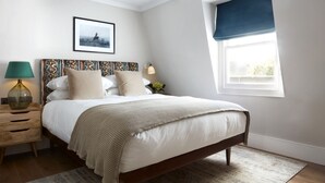 A neatly arranged bedroom with a bed, bedside table, lamp, and a window with a view. - The Hero of Maida (London)
