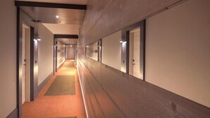Een lange, smalle hotelgang met tapijtvloeren en houten lambrisering.