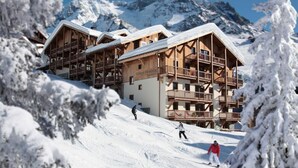 Een houten chalet met meerdere balkons en een bordje met de tekst 'Village Montana'.