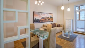 A modern living room with a glass coffee table, beige sofas, a white cabinet, and a large landscape painting on the wall. - Feel Belgrade Superior Apartment (Belgrade)