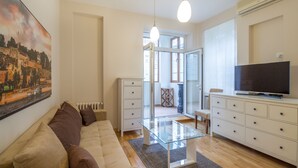 A modern living room with a glass coffee table, a sofa, a TV on a cabinet, and a painting on the wall. - Feel Belgrade Superior Apartment (Belgrade)