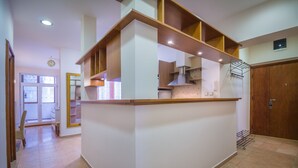 A kitchen with a central island, wooden cabinets, and a hanging rack. - Feel Belgrade Superior Apartment (Belgrade)