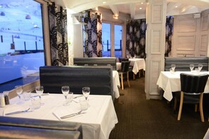 Restaurante com mesas preparadas para refeições, com vista para um teleférico.