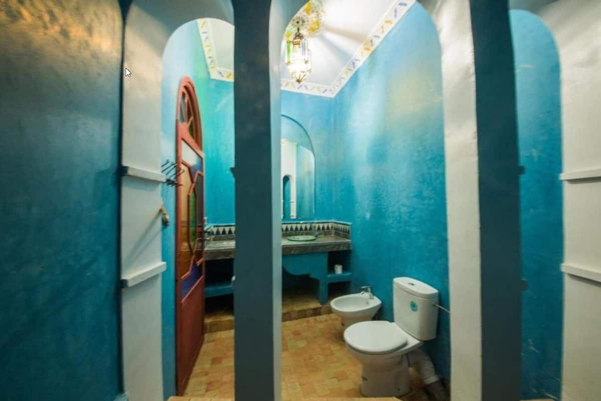 Ein Badezimmer mit blau-weißer Farbgestaltung, einem Waschbecken, einer Toilette und einem Bidet.