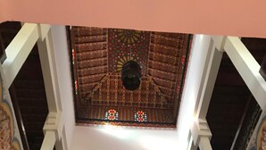 Ein Innenraum mit einer hohen, verzierten Decke, die ein zentrales Dome und Zierleisten aufweist.