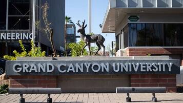 A sign for Grand Canyon University with a deer statue in front.