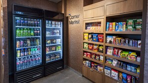 Een buurtwinkel met drankkoelingen en schappen vol snacks en houdbare producten.