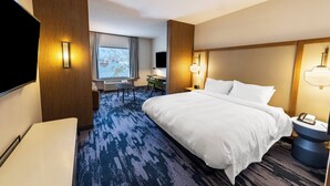 Een hotelkamer met een groot bed, een bureau, een stoel en een televisie.