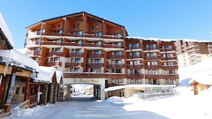 Een meerlaags hotel met een centrale ingang, balkons en een met sneeuw bedekte omgeving.
