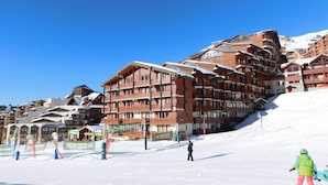 Een skigebied met meerlaags gebouwen, skiliften en een besneeuwde piste.