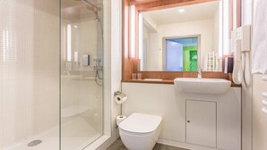 Une salle de bain moderne avec une douche à parois de verre, des toilettes blanches et un lavabo doté d’un plan de travail en bois.